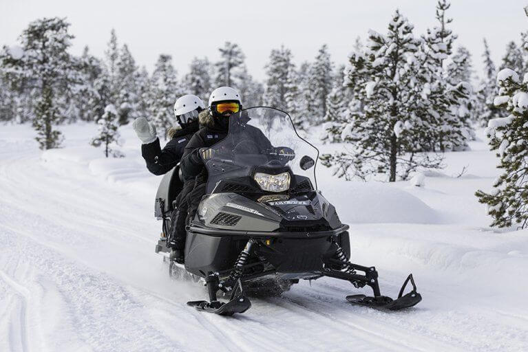 Woman waving during a snowmobiling excursion