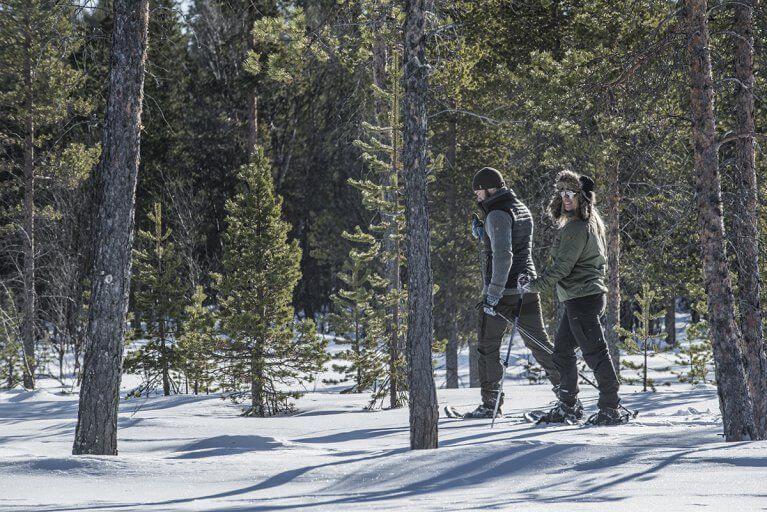 Man and woman on a snowshoe excursion through the woods