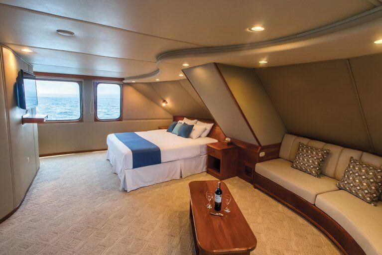 Spacious owners cabin with large sofa and TV on private luxury yacht cruising in the Galapagos Islands