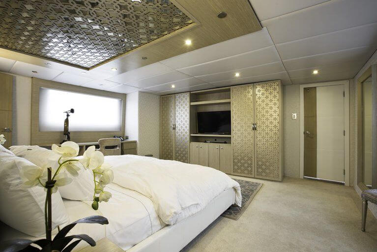 Large cabin with white bed and mirrored closets on private luxury yacht sailing in Galapagos Islands