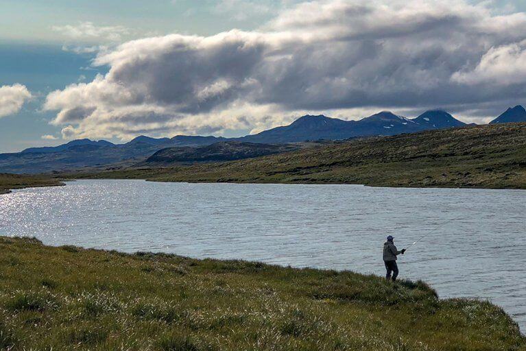 Man fishing in a peaceful lake in the Icelandic countryside