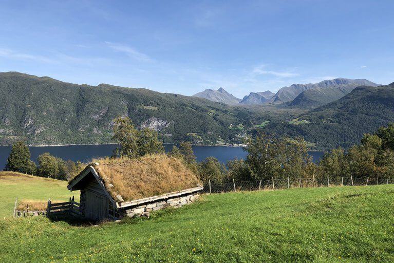 Traditional turf house with a view of a nearby lake during summer in NorwayTraditional turf house with a view of a nearby lake during summer in Norway