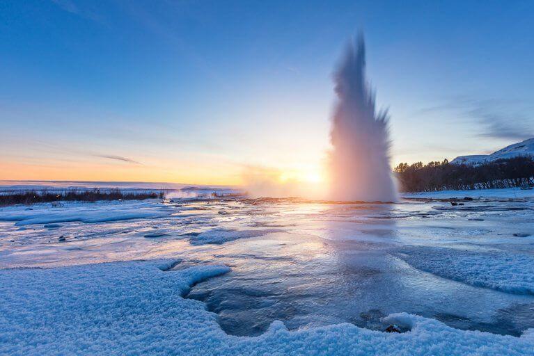 Iceland's Great Geyser erupting through an icy landscape