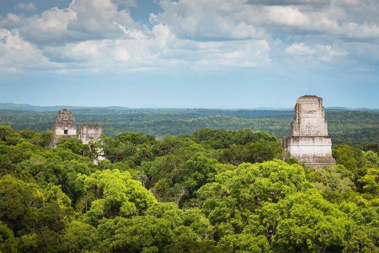 View of ancient Mayan ruins peeking above the canopy at the pre-Colombian citadel of Tikal