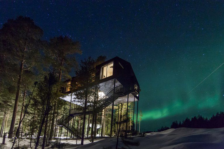Exterior view of Treehotel in Swedish Lapland at night with the Northern Lights in the sky