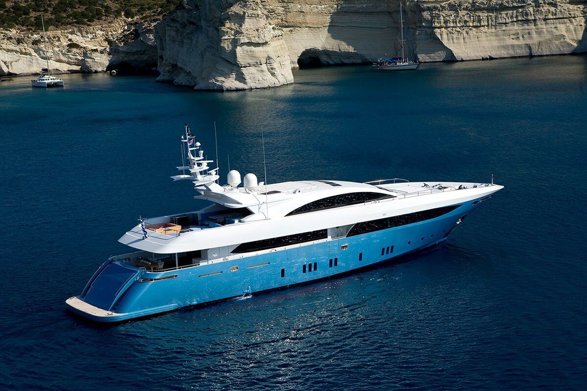 Luxury yacht sails near rocky cliffs of a Greek island