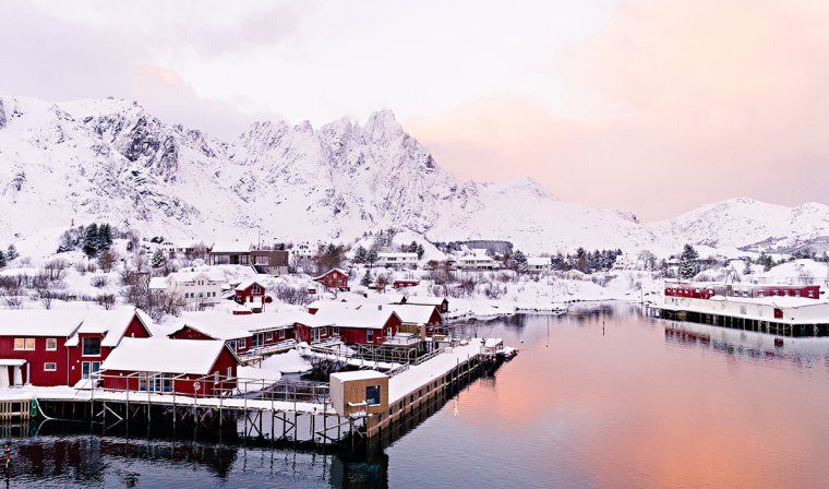 Fisherman's cabins covered in snow in Lofoten, Norway at dawn