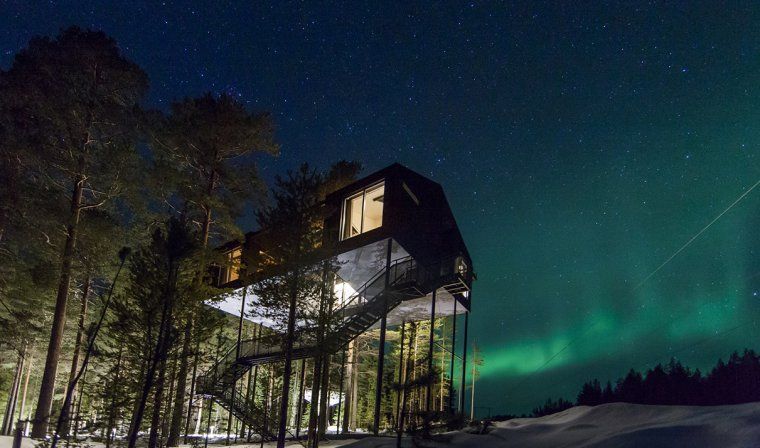 Exterior view of Treehotel in Swedish Lapland at night with the Northern Lights in the sky