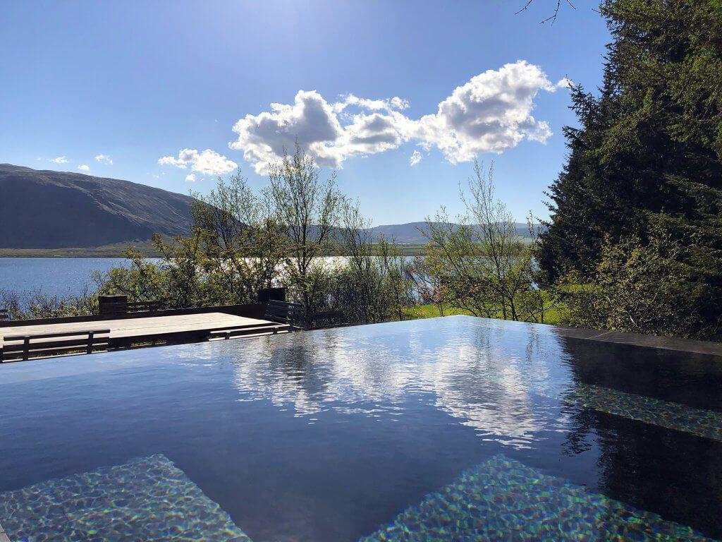 Infinity pool looking out over hills and lake of Icelandic countryside during summer
