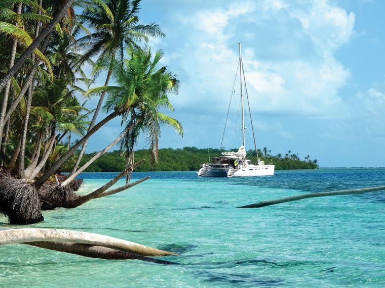 Catamaran sails in clear blue water of the San Blas Islands