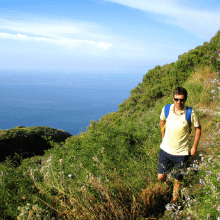 Man hikes along a green mountain with sea view in Sicily