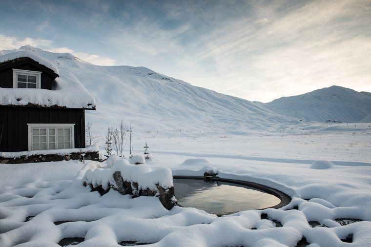 Small geothermal pool near building in snowy Icelandic countryside