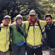 Group of four people stand together for a photo in the forest