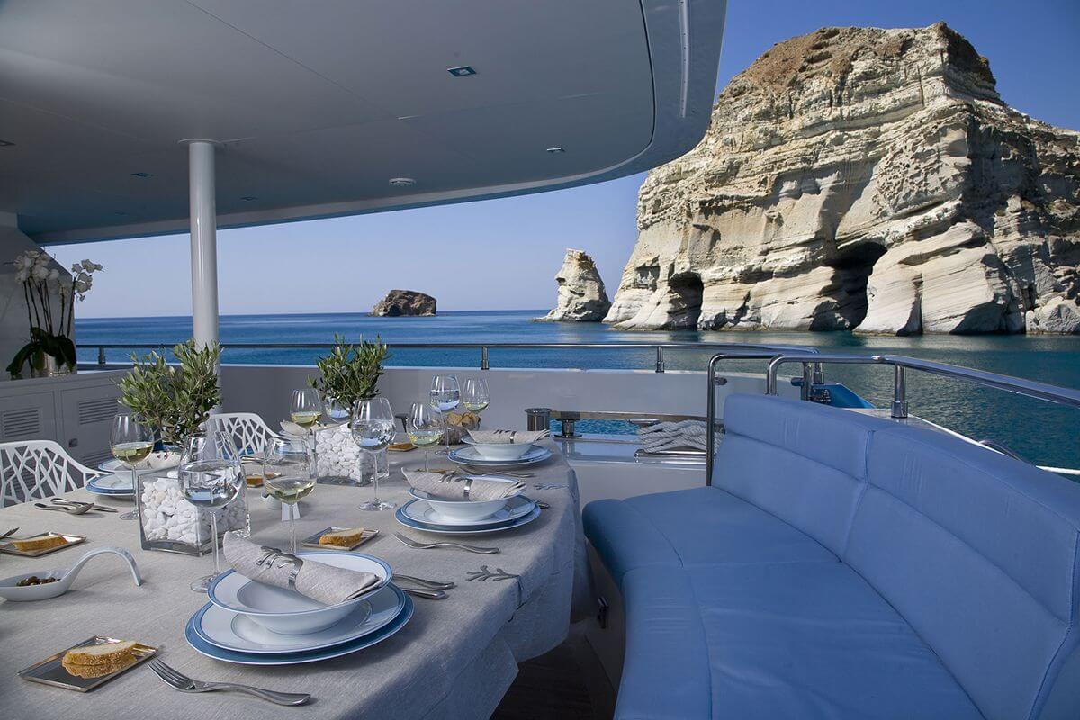 Luxury yacht sails near rocky cliffs of a Greek island