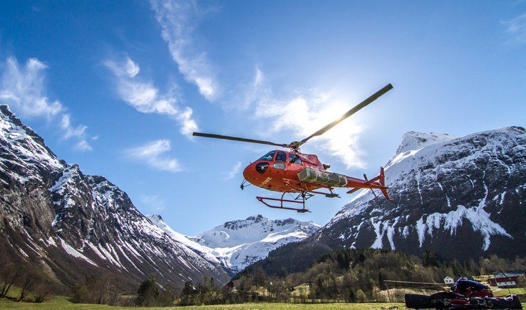 Helicopter takes off in a valley between mountains in Norway