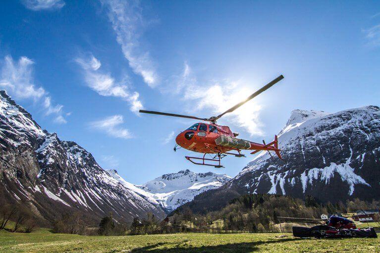 Helicopter takes off in a valley between mountains in Norway