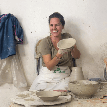 Woman shows her handmande wet clay bowl