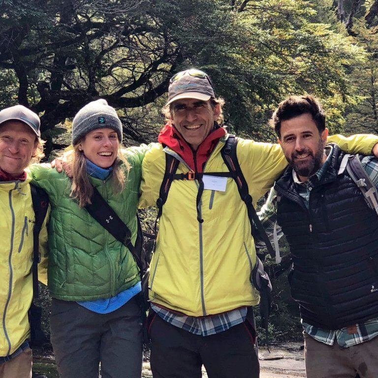 Group of four people stand together for a photo in the forest