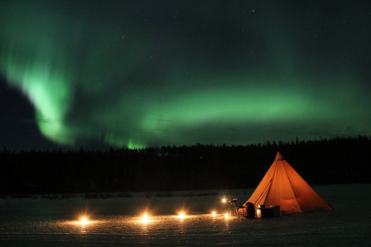 Indigenous Sami tent under the northern lights in Swedish Lapland during experiential travel