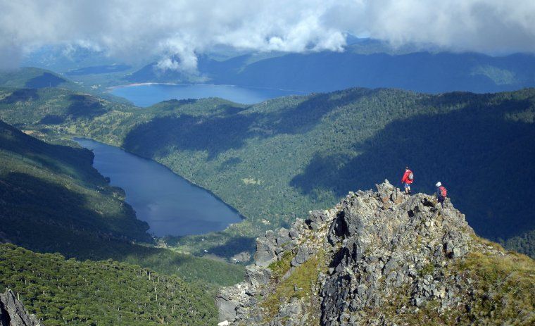 Two hikers admire the view of the Chilean Lake District from a mountain in one of Patagonia's natural wonders