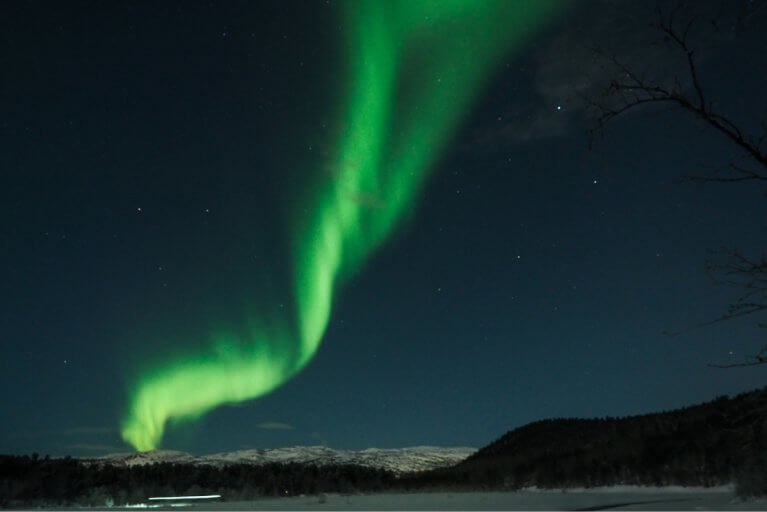 Green flashes of the northern lights above Arctic landscapes in Alta in Northern Norway
