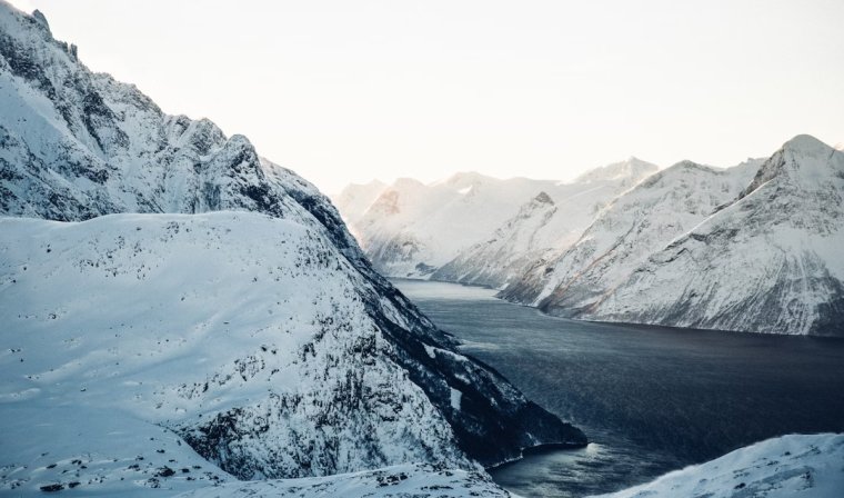 Aerial view of an icy river between snow-kissed mountains in Alta