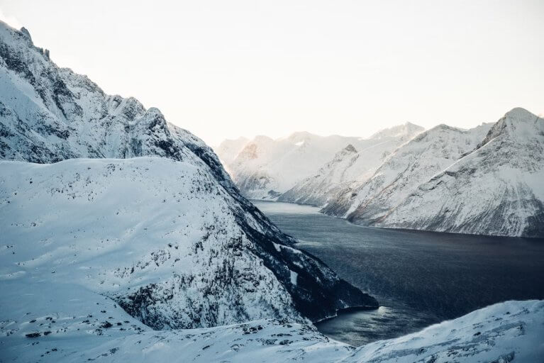 Aerial view of an icy river between snow-kissed mountains in Alta