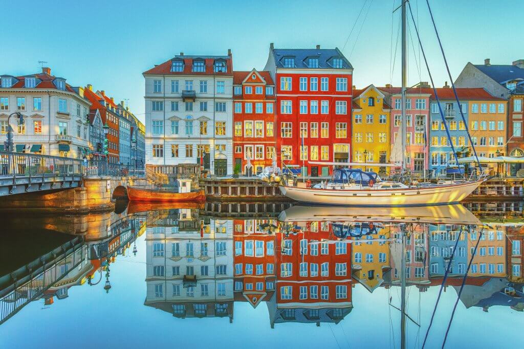 View of colorful houses reflecting on the water along Copenhagen's harbor during luxury tour