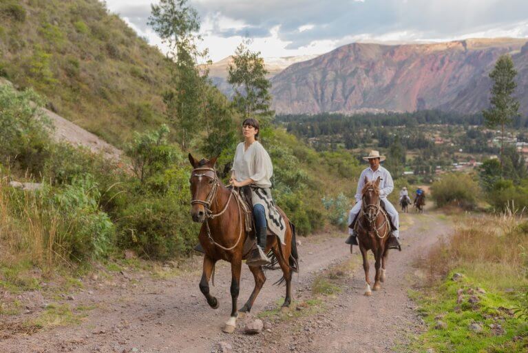 Two people horseback riding through the Sacred Valley during luxury tour of Peru