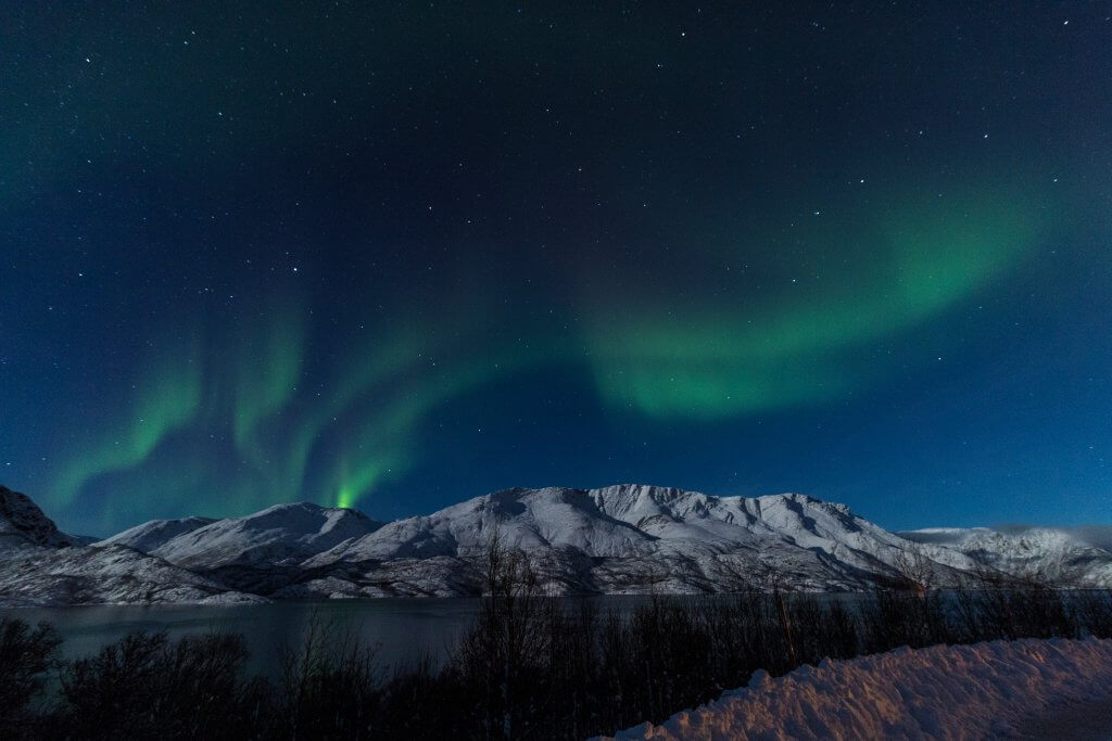 Wintery mountainous landscape in Northern Norway with the Aurora Borealis at night