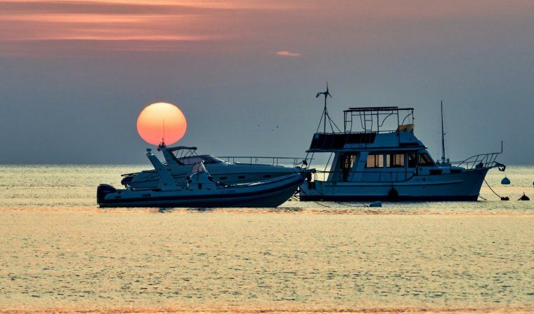 Stunning sunset in Corsica as boats sail past Santa Giuila Beach