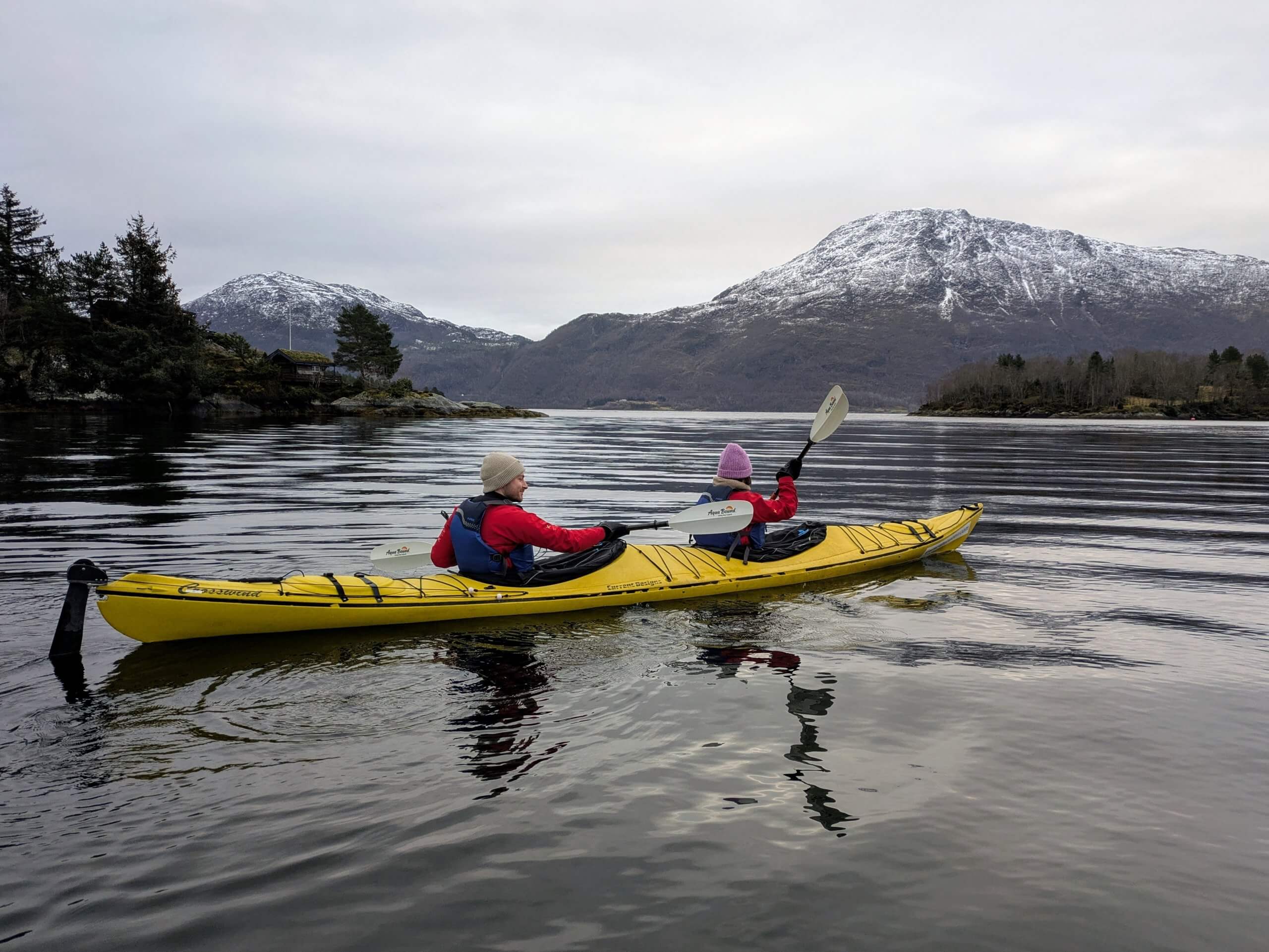 Two travelers kayaking across a fjord during an Arctic adventure tour in Norway
