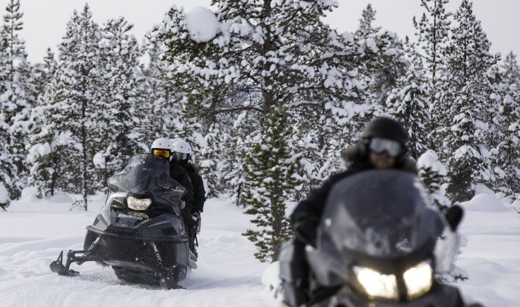 Two travelers enjoying a snowmobiling excursion in Swedish Lapland during winter wonderland activity