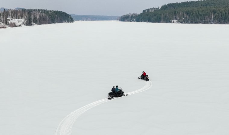 Travelers enjoying exciting snowmobiling adventure during luxury winter tour of swedish lapland