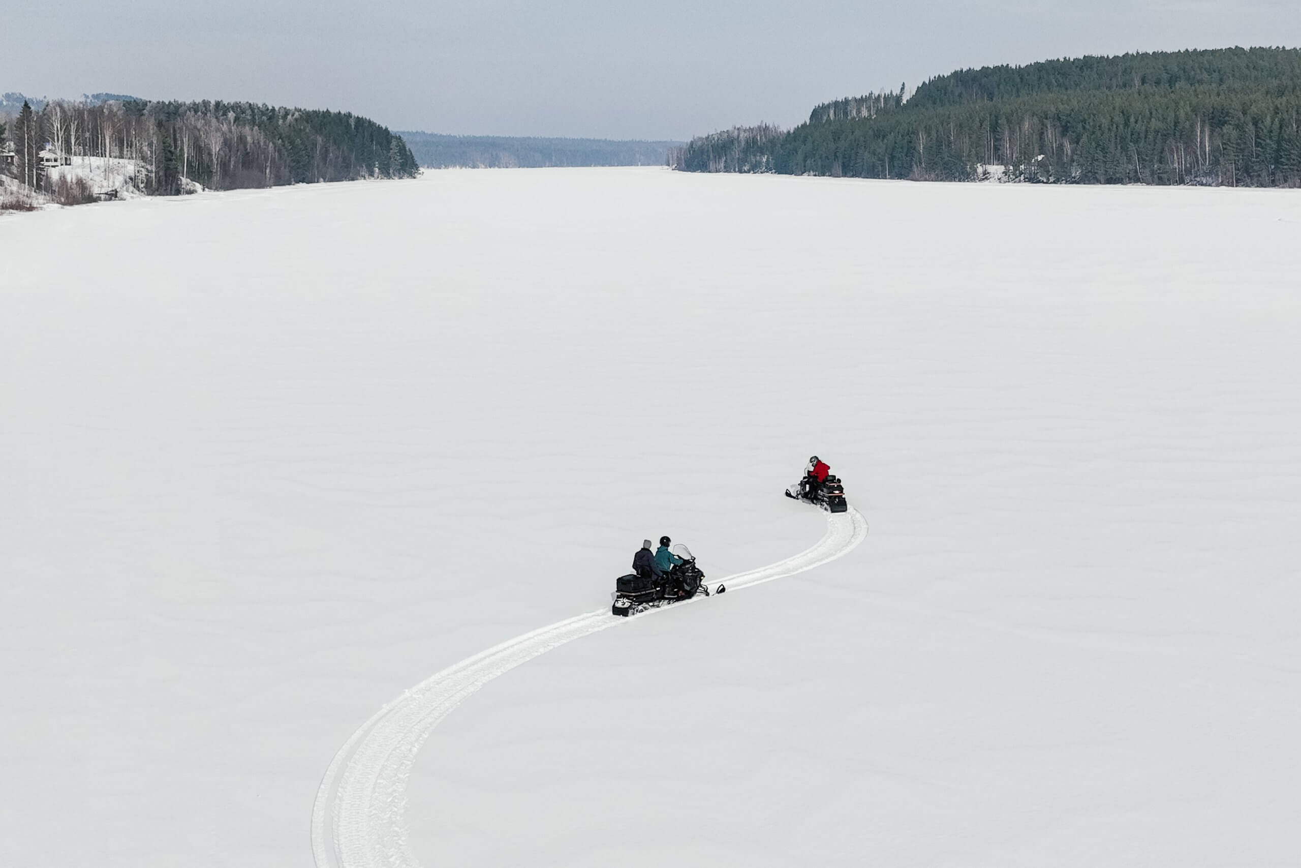 Travelers enjoying exciting snowmobiling adventure during luxury winter tour of swedish lapland