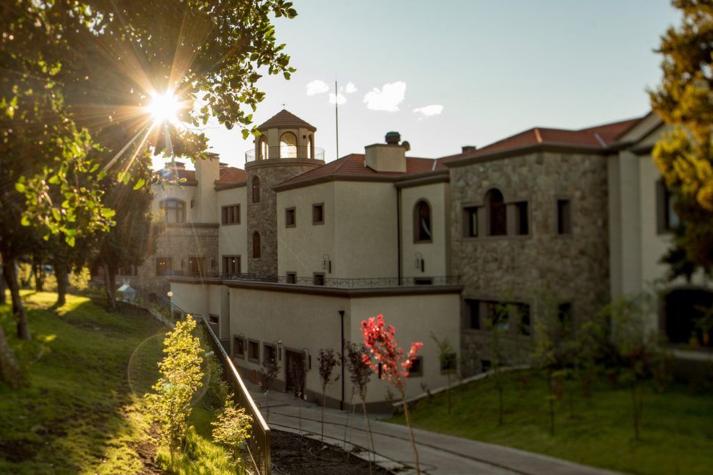 An exterior view of Villa Beluno with the sun shining through the trees.