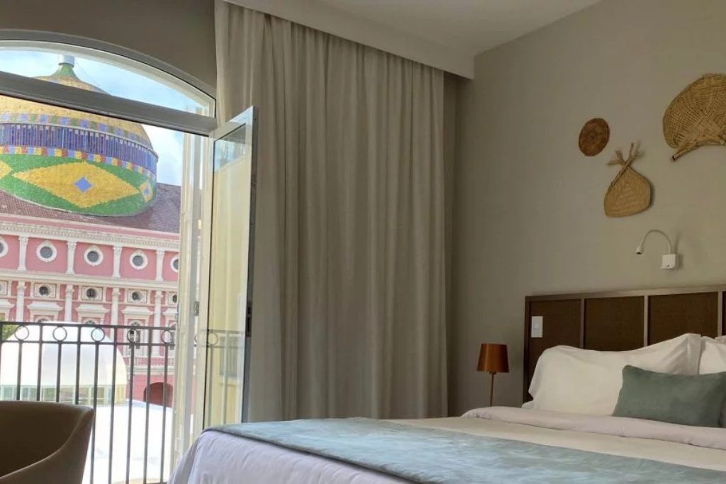 A view of one of the bedrooms with a bed and balconies at Hotel Juma Opera in Manaus.