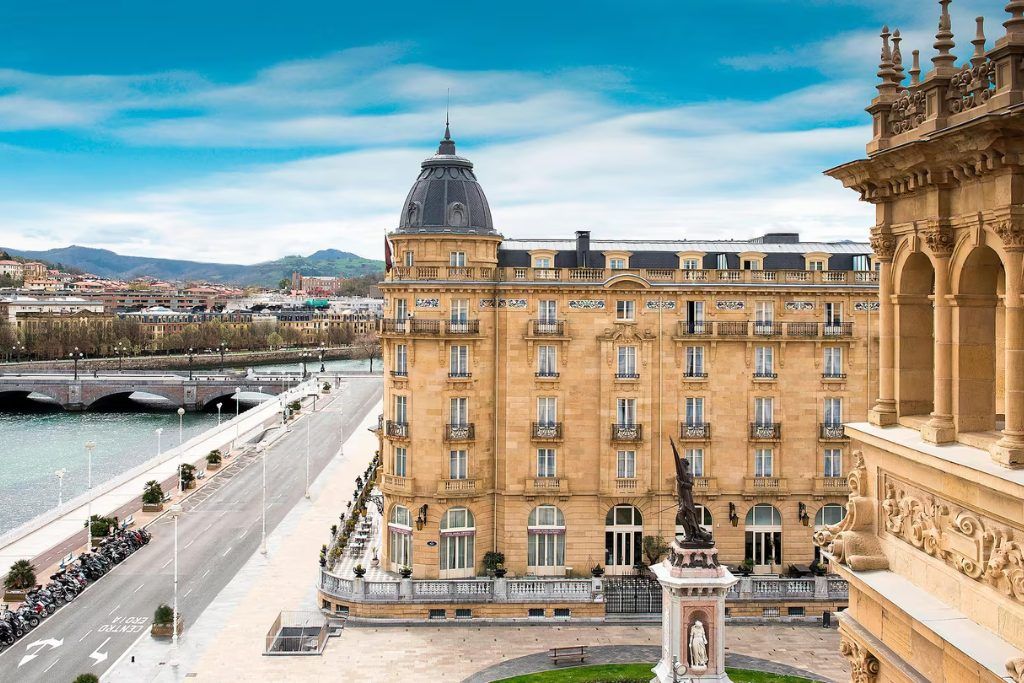 The exterior of Hotel Maria Cristina with a statue in the square below.