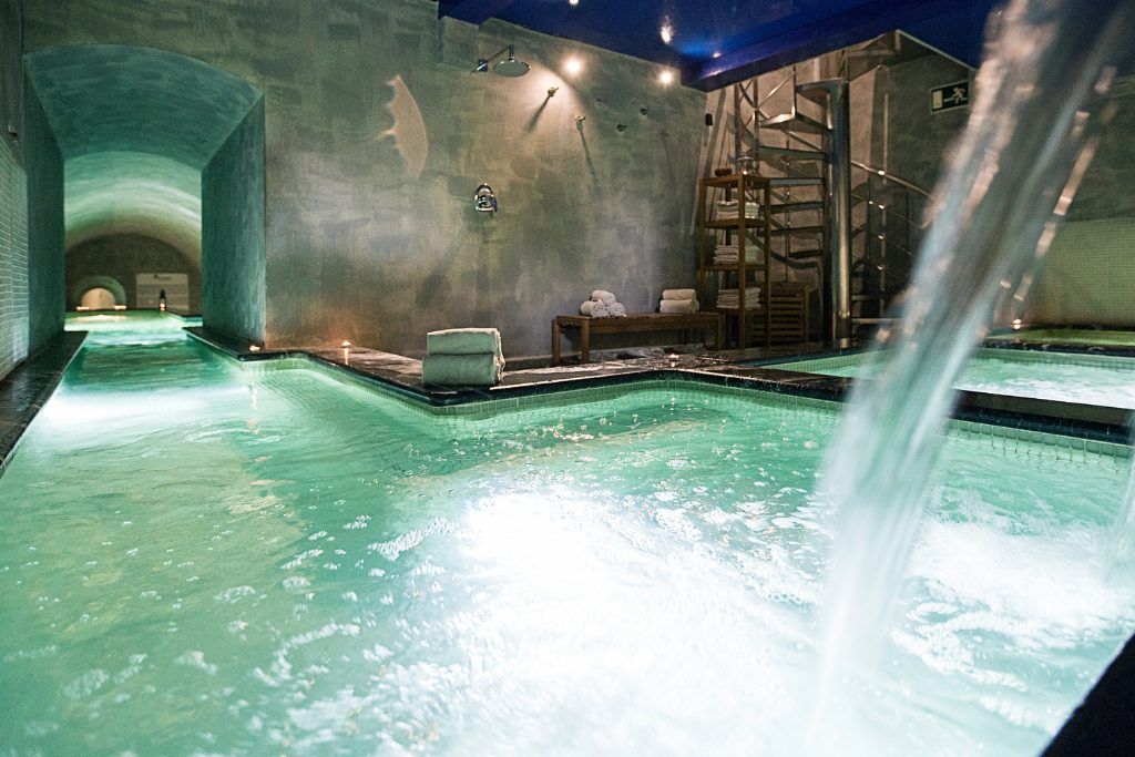 The indoor pool with a waterfall at Hospes Palacio del Bailio