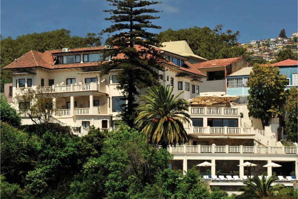 The exterior of Casa Higueras with a tall tree growing in front.