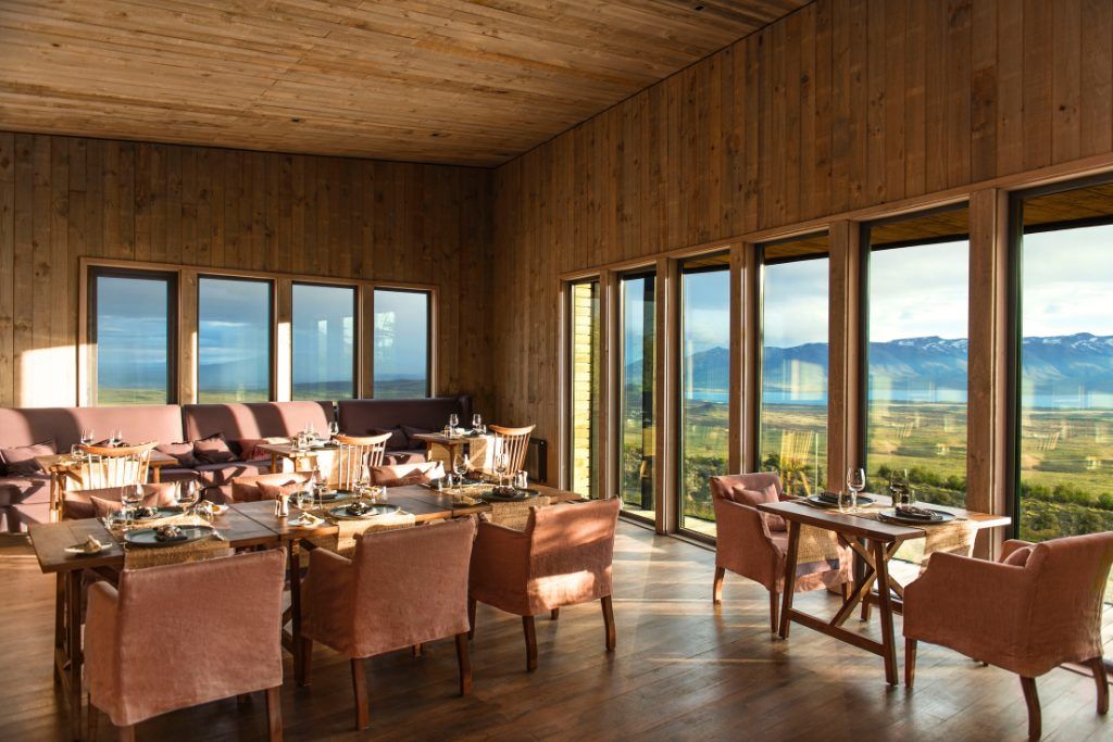 The dining room at Awasi Patagonia with wood paneled walls and large windows.