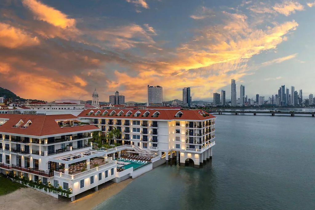 An aerial exterior view of the Sofitel Legend Casco Viejo with Panama City in the background.