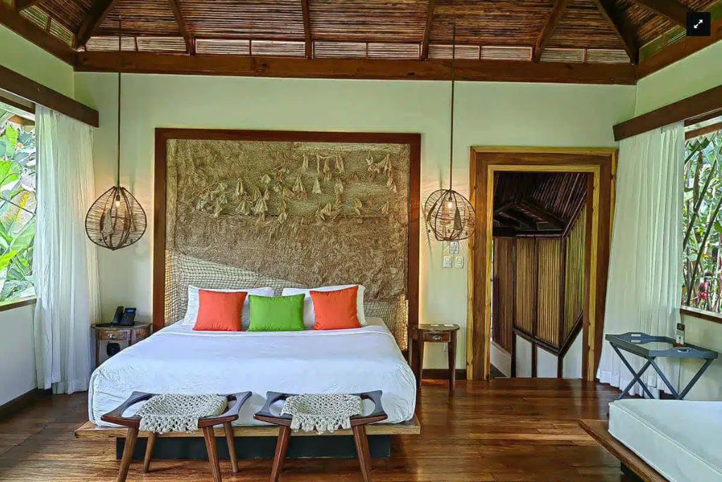 One of the rooms in the Pacuare Lodge with colorful pillows on the bed.