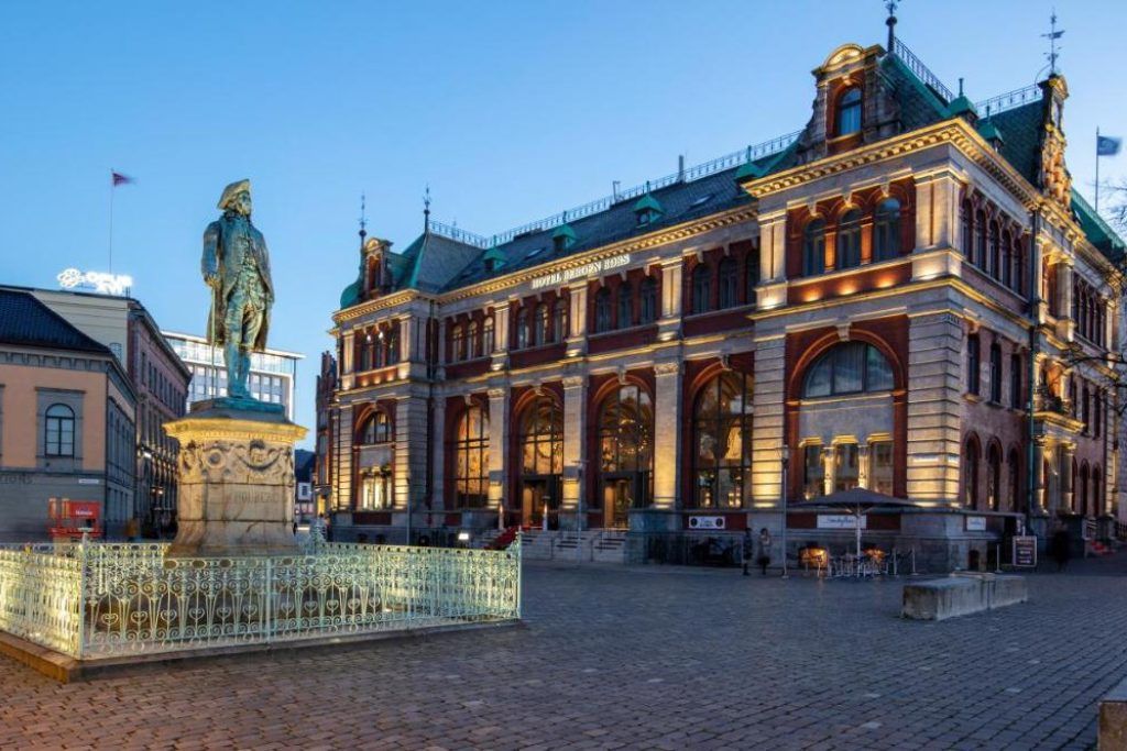 The exterior of the Bergen Børs hotel with a statue in the square.