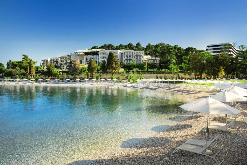 A view of Monte Mullini from the waterfront with beach loungers by the water.