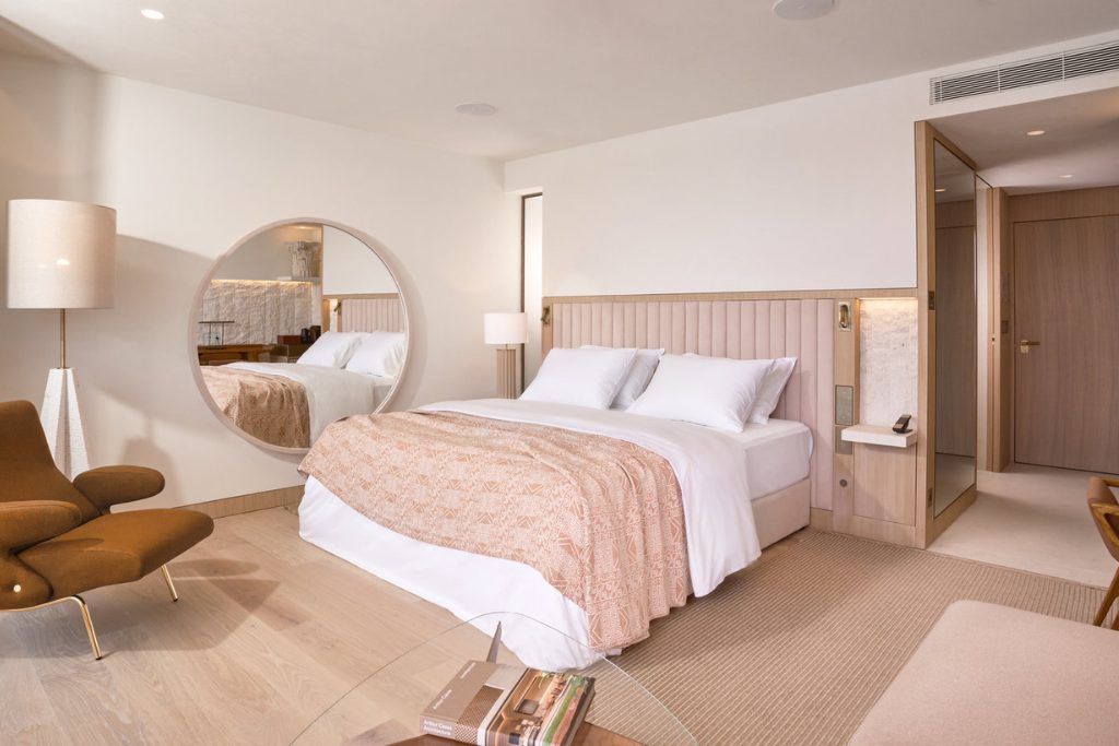 A room with a large bed with pink accents and a round mirror at Villa Dubrovnik.