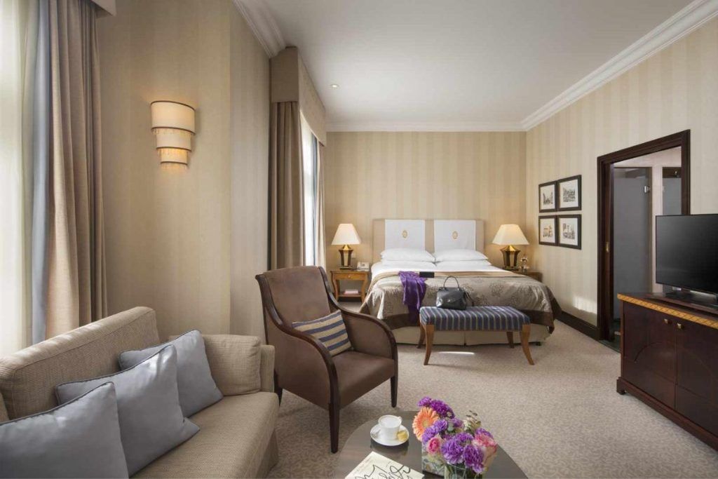 One of the rooms with a couch and flowers on the table at Esplanade Zagreb.
