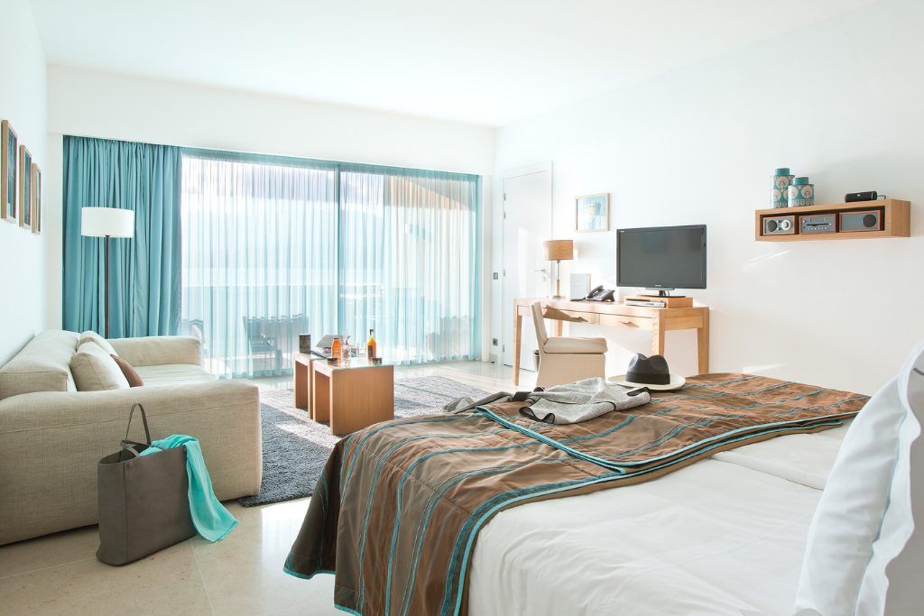 One of the sunny rooms with light furnishings and a large window at Casadelmar.