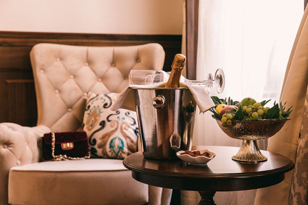 A bottle of champagne and fruit on an end table in one of the rooms at the Cardo Hotel