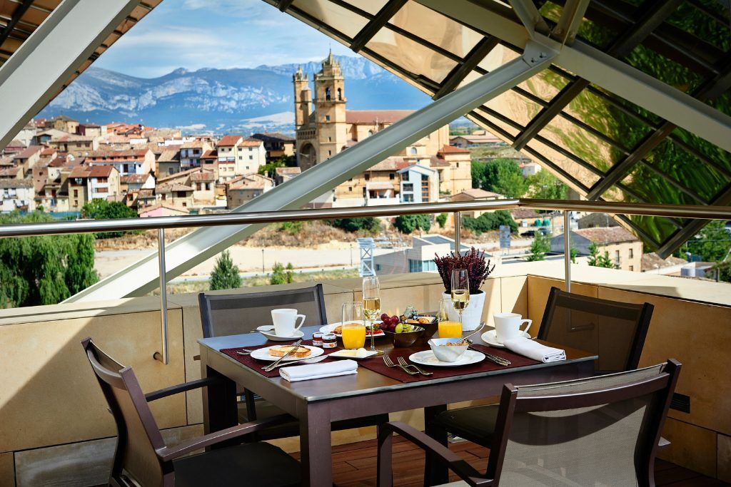 A table set with breakfast at Hotel Marques de Riscal overlooking the city.